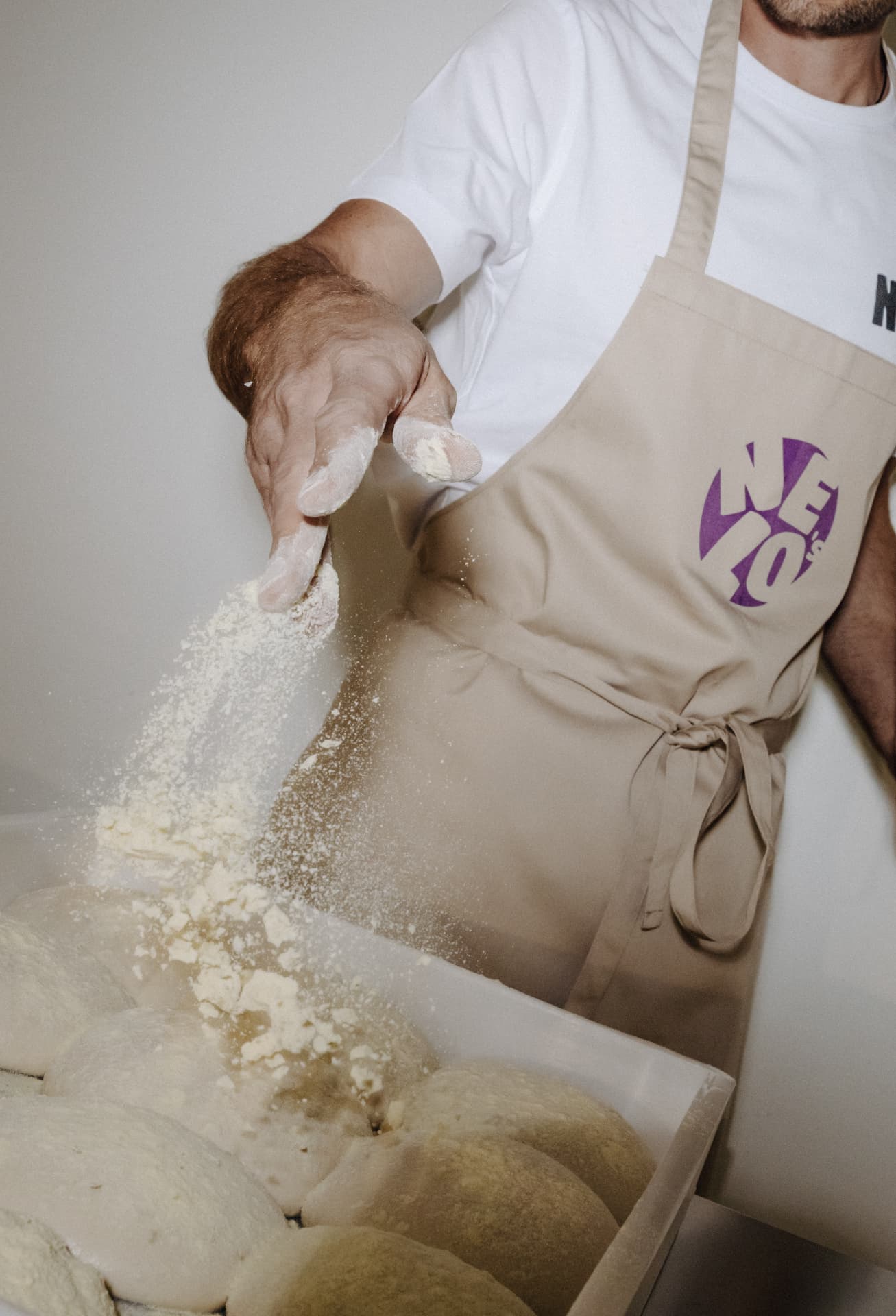 Pizzaiolo bestäubt die lang gereiften Teiglinge mit Mehl
